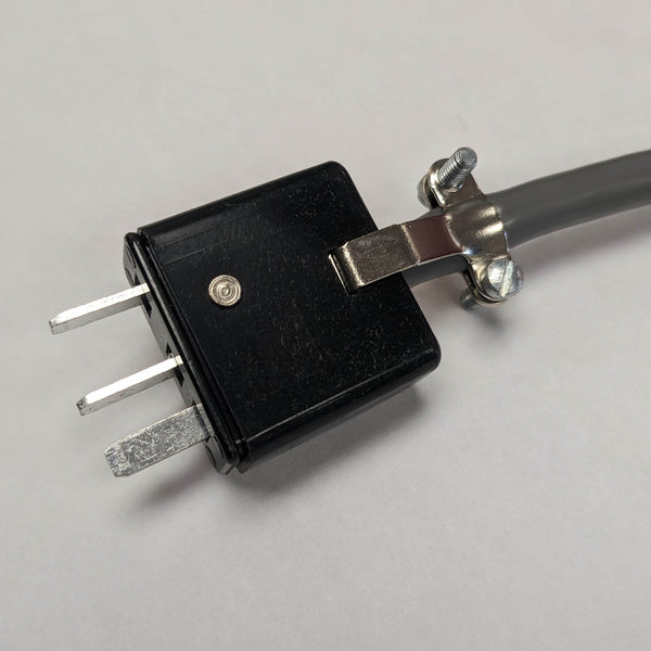 Black rectangular plug end of a round, silver foot pedal with a black center, designed for use with Instantron and Fischer electrolysis machines. The pedal has a smooth, flat surface for easy foot activation, and connects to the machine with a flexible black cord.