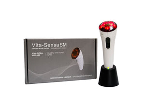 White handle with red end on the Vita-Sensa SM facial stimulator, a handheld device with a sleek, ergonomic design. It features 10 small metal electrodes and 5 red light emitting diodes (LEDs) for microcurrent, light therapy, and vibromassage. The device comes with a gray transformer and base, a user guide, and a portable travel kit.